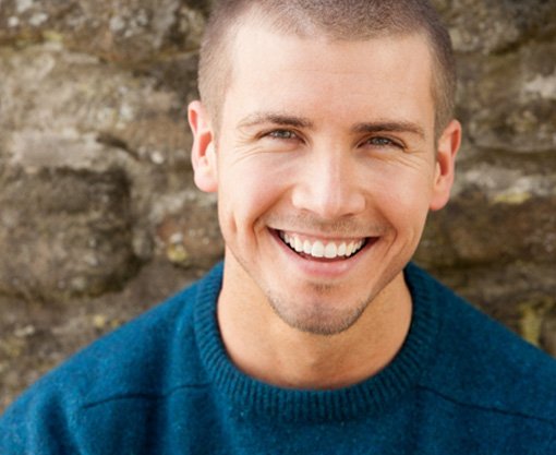 Close-up of man in front of stone wall smiling 