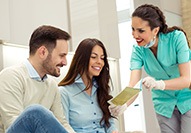 Dental assistant showing smiling couple form