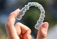 a hand holding an Invisalign tray