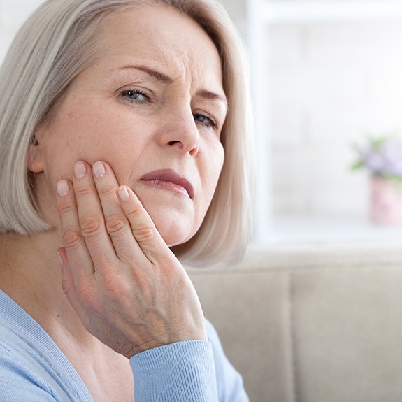 Senior woman sitting on couch with tooth pain