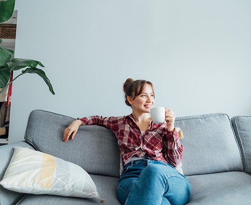 Smiling woman sitting on couch and drinking tea